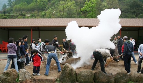 Tourists enjoy a steam pit experience. Afterwards they eat sweet potatoes and eggs out of the steam pit. 